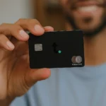Persona sosteniendo una tarjeta Tomo Credit Card World Elite Mastercard en posición horizontal, fondo claro
